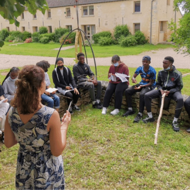 French youth listen to a facilitator speak outdoors