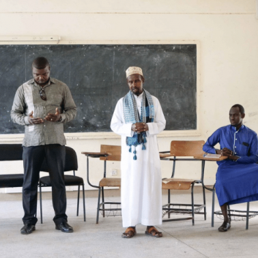 Kenyan pastor, imam, and facilitator hold a prayer before an outreach event in Kenya