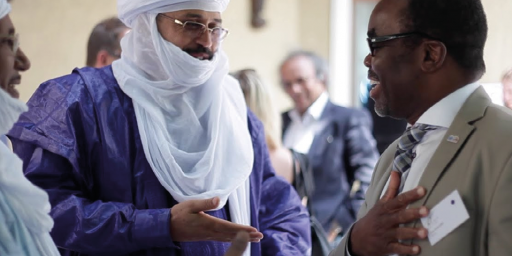 Arab man with turban and face cover speaks with African man in business suit